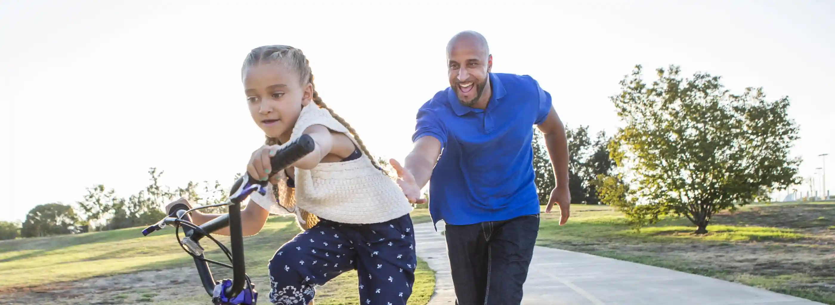 Happy father teaching daughter to ride a bike