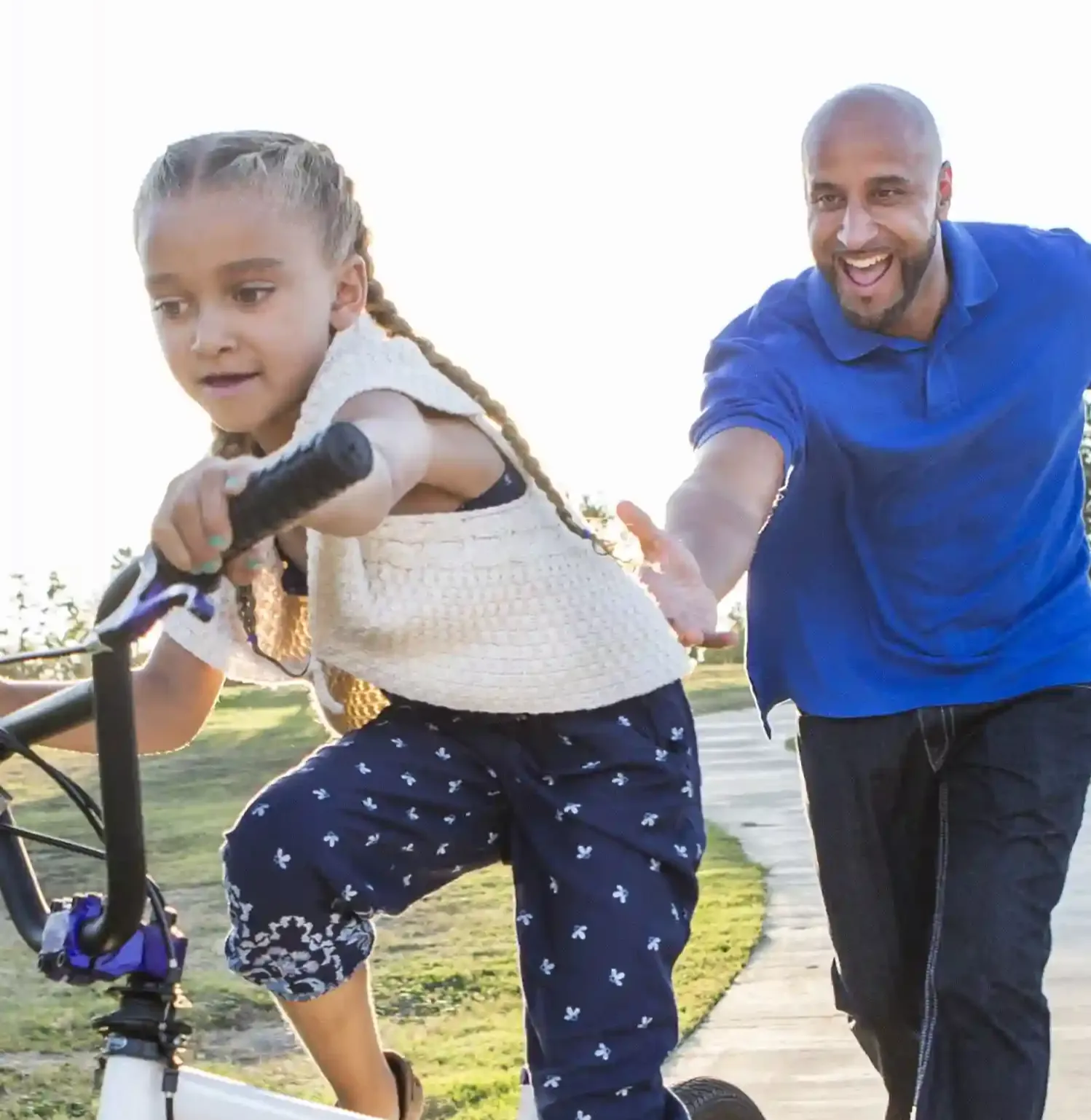 Happy father teaching daughter to ride a bike